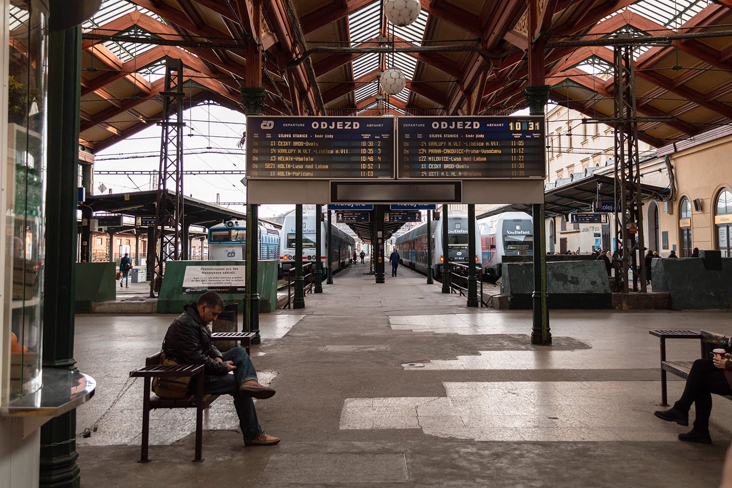 In Prague station a man sits reading his phone